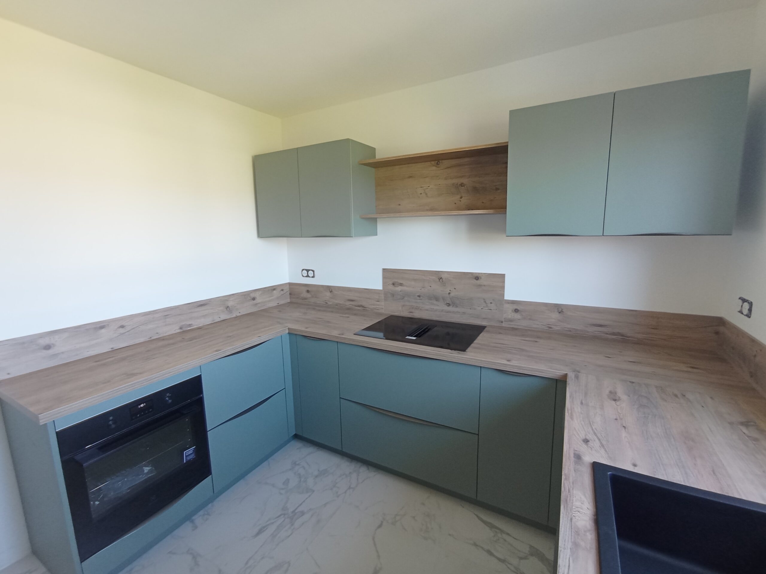 Cuisine moderne en U avec plans de travail bois et meubles vert sauge; cuisson intégrée et rangements muraux. comment moderniser une cuisine proche.